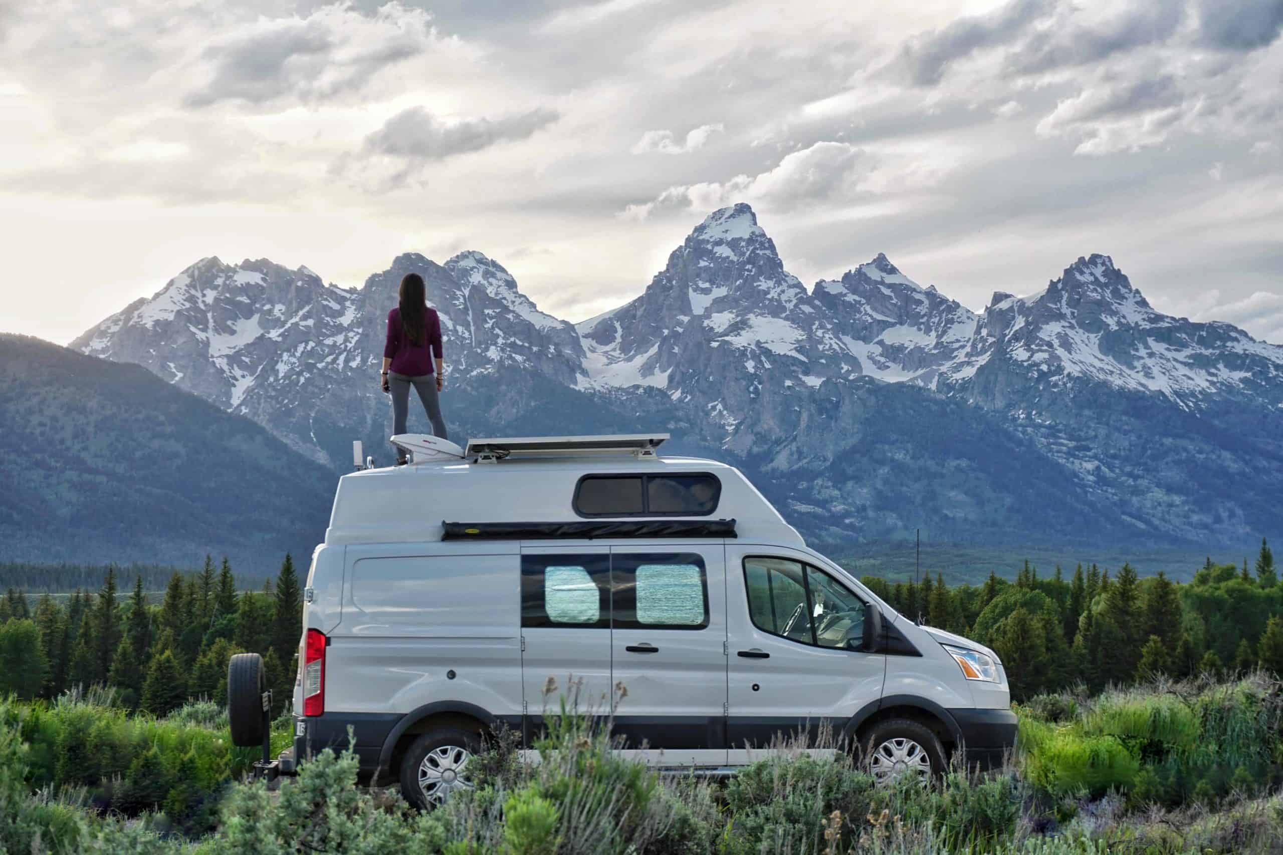 girl on van in front of grand teton mountains